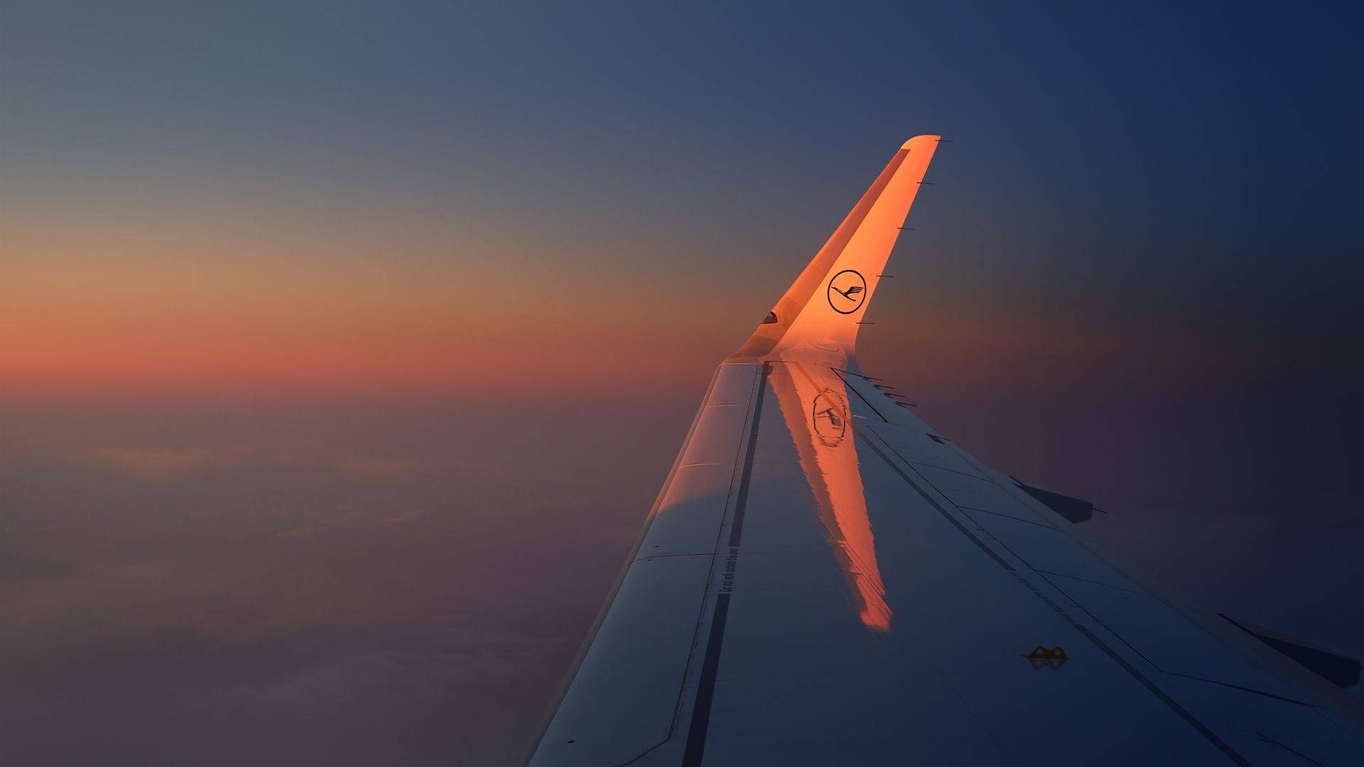 Lufthansa aircraft wing silhouetted against a sunset sky